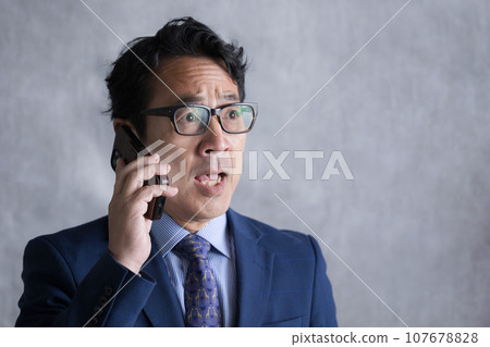 商人用智慧型手機打電話,感到驚訝 商人用智慧型手機打電話,感到驚訝 107678828