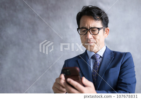 Middle-aged businessman operating a smartphone Middle-aged businessman operating a smartphone 107678831