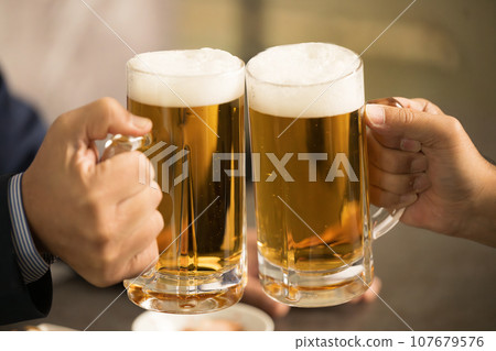 Businessman toasting, close-up of faceless hand holding draft beer 107679576