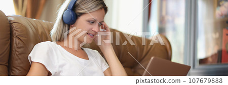 Woman works on laptop and listens to music in headphones 107679888