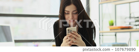 Satisfied woman sends messages to boyfriend from office Satisfied woman sends messages to boyfriend from office 107679890