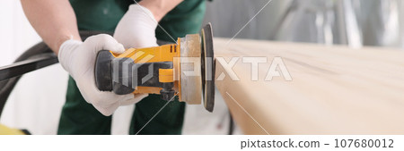 Carpenter processes wooden table with grinder machine Carpenter processes wooden table with grinder machine 107680012