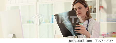 Woman studies radiograph image of joint making notes Woman studies radiograph image of joint making notes 107680056