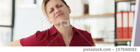 Blonde secretary feels acute pain in lower back at workplace Blonde secretary feels acute pain in lower back at workplace 107680093