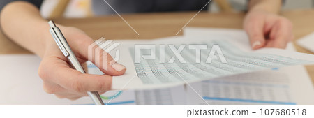 Woman examines investigation document sitting at table 107680518