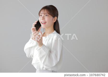 A young woman happily making a phone call_her left hand moves 1 107680742