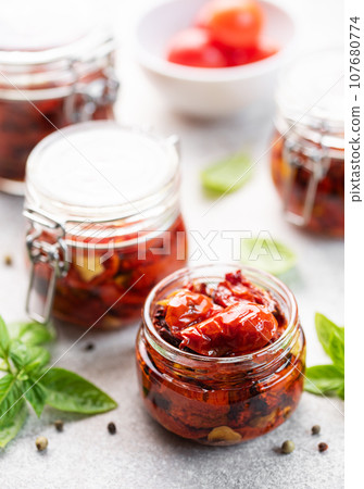 Jar with sun dried tomatoes with fresh herbs and spices. Jar with sun dried tomatoes with fresh herbs and spices. 107680774