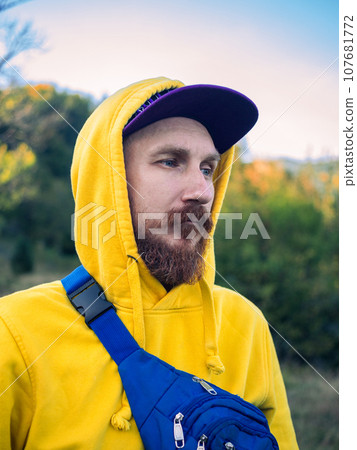 Red bearded millennial man with mustache in yellow hoody smiling portrait closeup Backpacker hiking climbing mountains 107681772