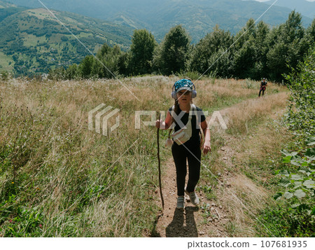 Little girl climbs on Carpathian mountains peak in Zakarpattya village Ukraine Europe. Family walks on scenic landscape. 107681935