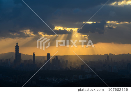 At dusk, the sun breaks through the clouds and shines on Taipei City. 107682536