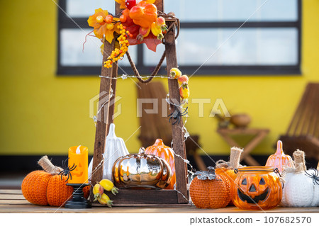 Autumn decor on the porch of the house outside in the yard of pumpkin, lantern, garlands, hats, jack lantern. Halloween party, autumn mood, Harvest festival 107682570