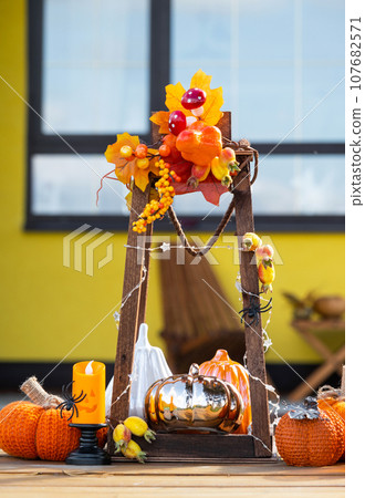 Autumn decor on the porch of the house outside in the yard of pumpkin, lantern, garlands, hats, jack lantern. Halloween party, autumn mood, Harvest festival 107682571