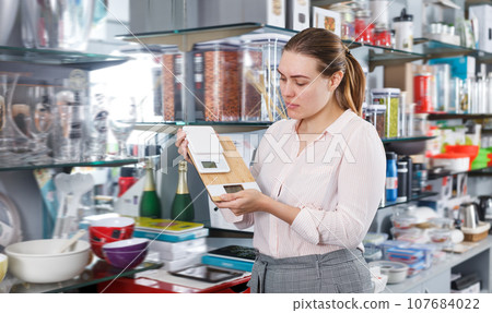 Young female customer choosing new kitchen scale Young female customer choosing new kitchen scale 107684022