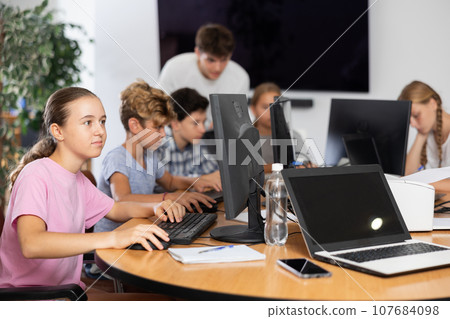 Preteen girl working with computer programs in training room Preteen girl working with computer programs in training room 107684098