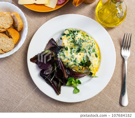 Omelette with spinach served on platter 107684182