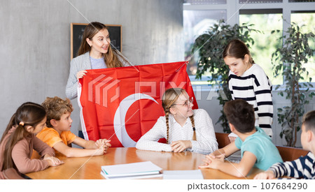 Female teacher working with teenage students in school class, talking about national flag of Turkey at history lesson 107684290