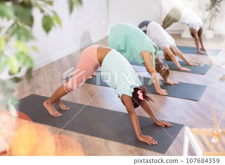 Training yoga kids on yoga mat in gym. 107684359