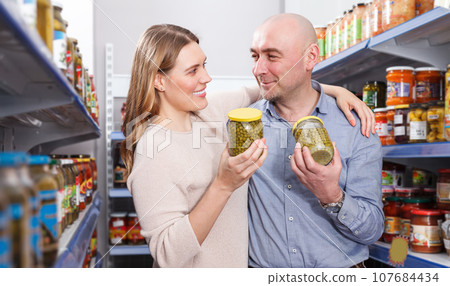 Smiling woman and husband looking pickle goods in supermarket 107684434