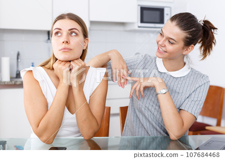 Young girl showing betrothal ring to upset female friend 107684468