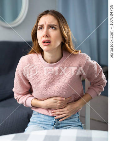 Young woman suffering from abdominal pain 107684759