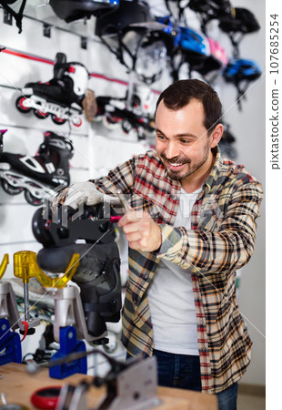 Male repairer fixing roller-skates in sports store Male repairer fixing roller-skates in sports store 107685254