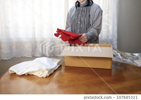 一位女士在網路上購買衣服並立即打開。 一位女士在網路上購買衣服並立即打開。 107685321