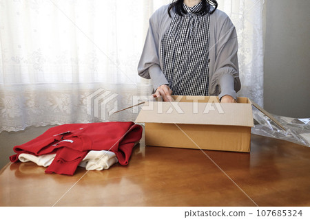 A woman purchases clothes online and immediately opens them. 107685324