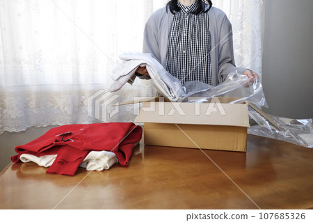 A woman purchases clothes online and immediately opens them. 107685326