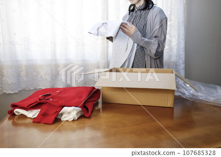 A woman purchases clothes online and immediately opens them. 107685328