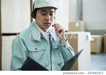 倉庫裡一名年輕工人透過對講機發出指令 倉庫裡一名年輕工人透過對講機發出指令 107685871