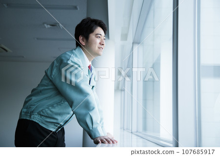 Young male engineer in work clothes working in the office Young male engineer in work clothes working in the office 107685917