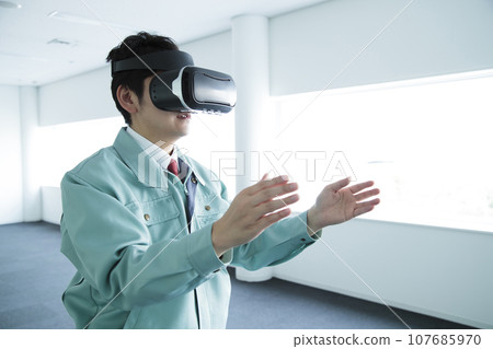 Young male engineer in work clothes watching VR in the office 107685970