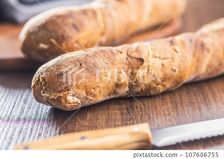 Wholegrain rustical baguette on wooden table. 107686755