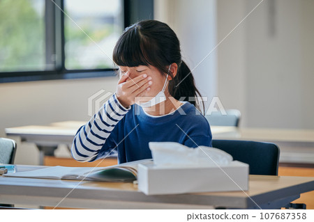 Elementary school girl holding her nose with her hand Elementary school girl holding her nose with her hand 107687358