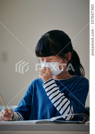 Elementary school girl who has a cold and coughs 107687360