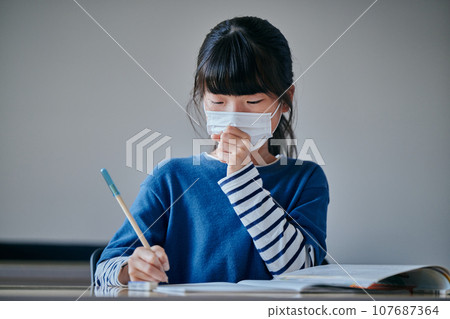 Elementary school girl who has a cold and coughs Elementary school girl who has a cold and coughs 107687364