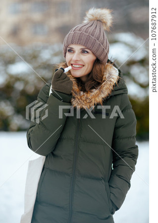 smiling modern woman outdoors in city park in winter 107687912