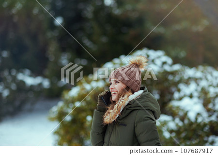 smiling modern woman outdoors in city park in winter 107687917