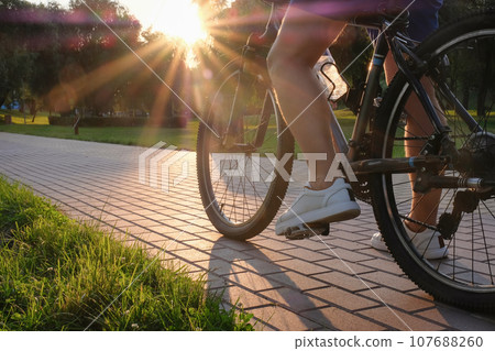 Man rides a bike outdoors in the park on a sunny day at sunset close-up. Active lifestyle 107688260