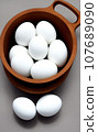white eggs in a wooden bowl 107689090