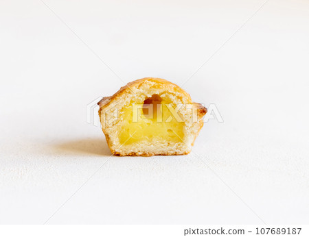 Half of Pasticciotto leccese pastry filled with egg custard cream on a white table, close up 107689187