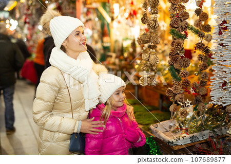 Smiling woman with small daughter in Christmas market Smiling woman with small daughter in Christmas market 107689877