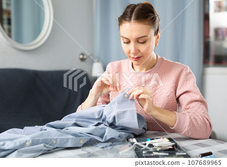 Woman sewing up shirts at home 107689965