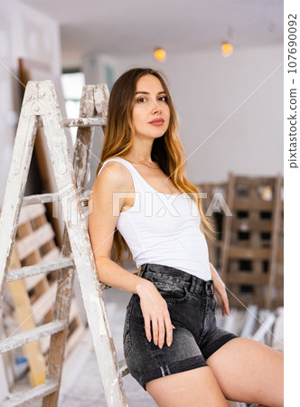 Attractive young woman poses on a construction site 107690092