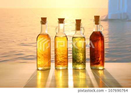 Four glass bottles with different colored versions of vegetable oils Four glass bottles with different colored versions of vegetable oils 107690764