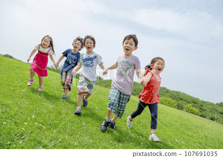 Elementary school students playing on the grass in the park Elementary school students playing on the grass in the park 107691035