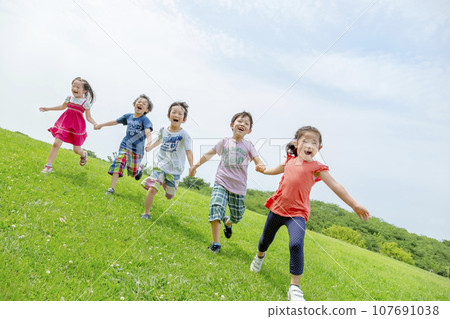 Elementary school students playing on the grass in the park 107691038