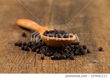 black pepper on wooden spoon 107691117