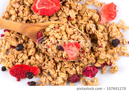 Muesli oat cereals close up background with dry fruits in wooden spoon Muesli oat cereals close up background with dry fruits in wooden spoon 107691278