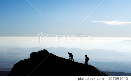 Silhouette of hikers on mountain top 107691440